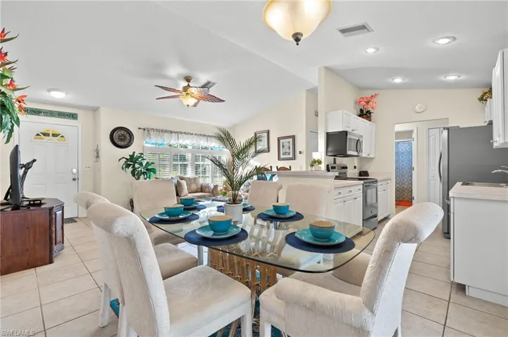 Tiled dining room featuring ceiling fan, sink, and vaulted ceiling
