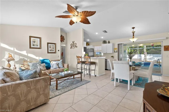 Tiled living room with ceiling fan and lofted ceiling