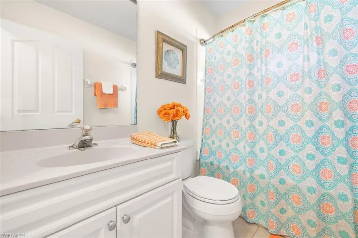 Bathroom featuring tile patterned floors, vanity, toilet, and a shower with curtain