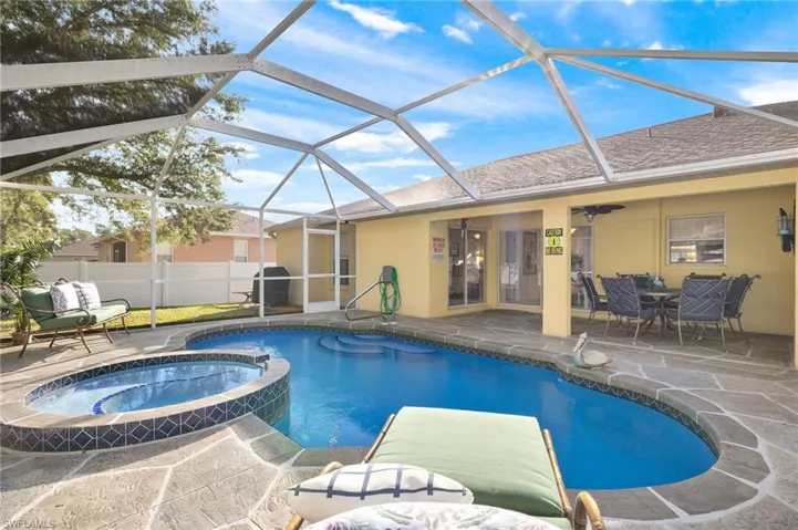 View of swimming pool with an in ground hot tub, glass enclosure, ceiling fan, and a patio area