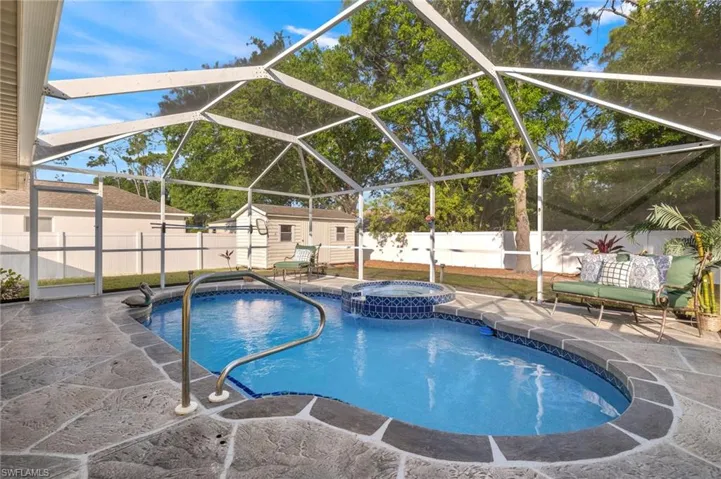 View of pool featuring an in ground hot tub, a patio, glass enclosure, and a storage unit