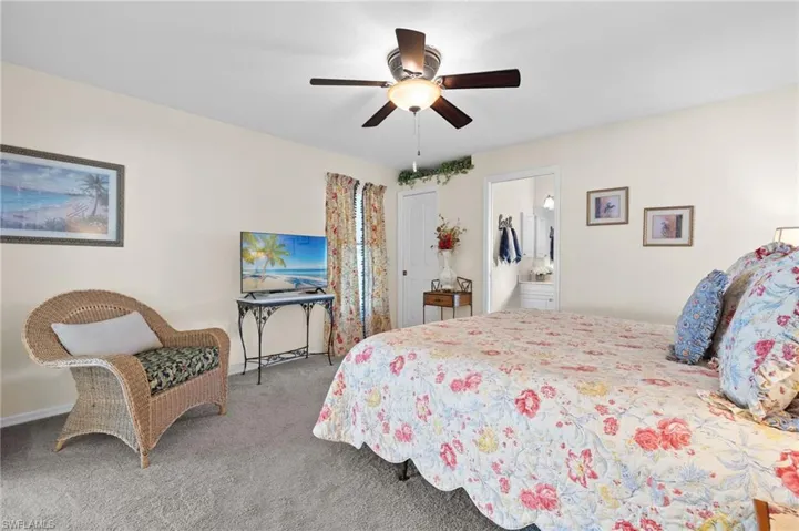 Carpeted bedroom featuring ceiling fan and ensuite bathroom