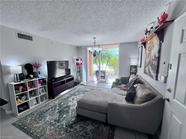 Living room with suspended lighting, a textured ceiling, and tile patterned floors
