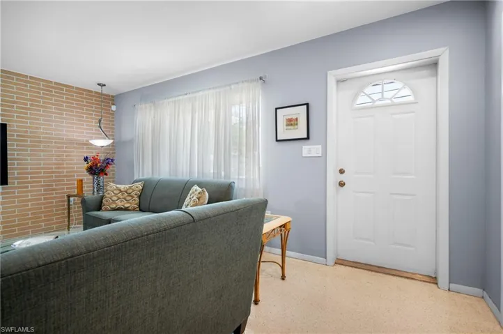Entry door with an arched transom window, light blue painted walls, and a brick accent wall