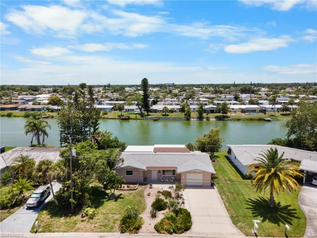 Waterfront property featuring a single-story residence with a light-colored exterior, an attached garage, and a concrete driveway