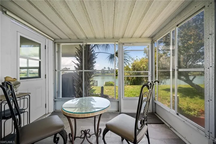 Screened patio featuring a slatted ceiling, tile flooring, and waterfront scenery