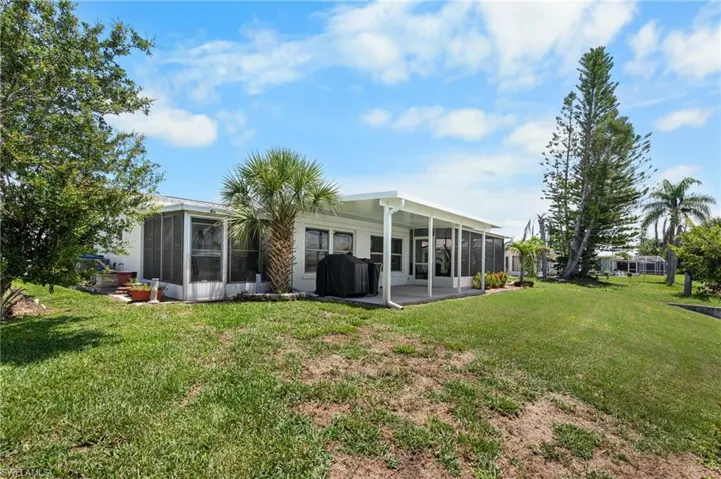 Expansive green lawn with mature palm trees and established landscaping
