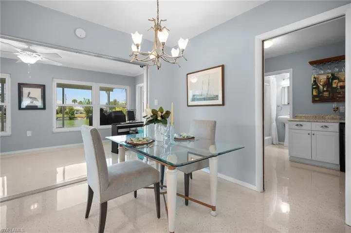 Dining area featuring a contemporary chandelier, light-toned walls, and reflective flooring