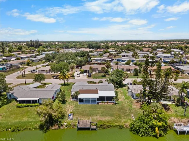 Waterfront property featuring a private dock, screened lanai, and an expansive lawn