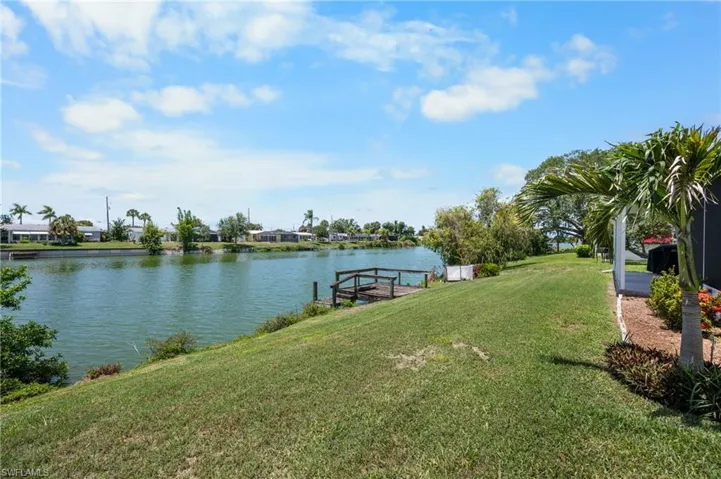 Expansive waterfront property featuring a lush green lawn leading to a private wooden dock