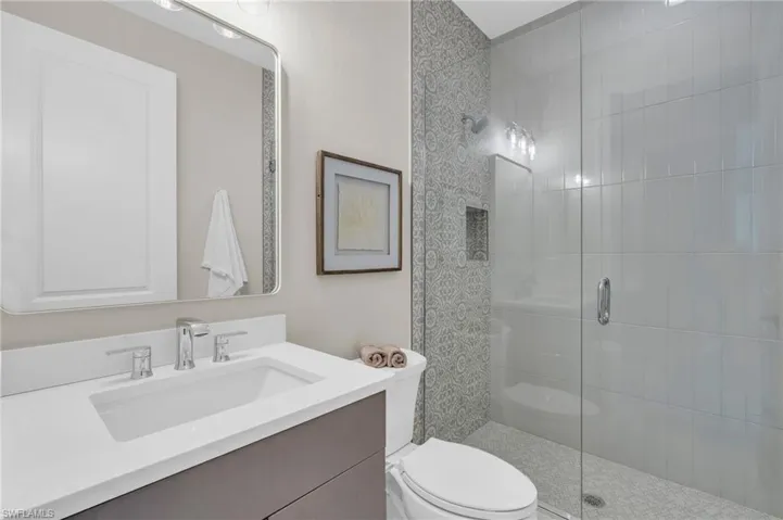 Bathroom with vanity, a shower with shower door, and toilet