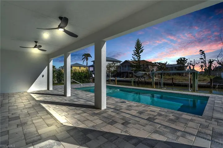 VIRTUALLY ENHANCED - Pool at dusk with ceiling fan and a patio area