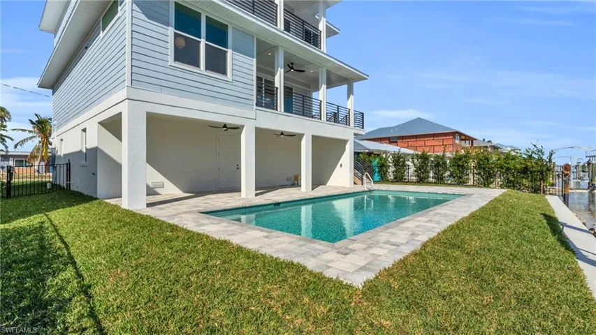 Rear view of house with ceiling fan, a yard, a balcony, a fenced in pool, and a patio area VIRTUALLY ENHANCED