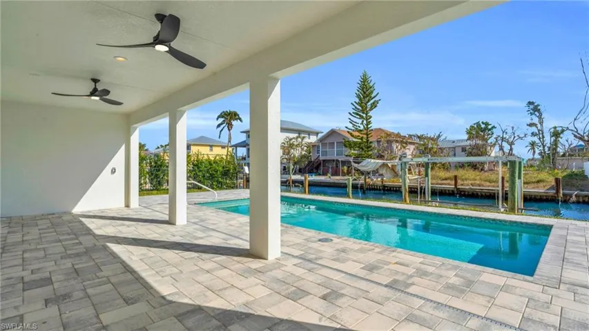 VIRTUALLY ENHANCED - View of swimming pool featuring a water view, ceiling fan, and a patio area