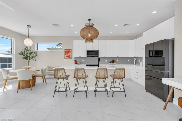 Kitchen with backsplash, sink, white cabinets, and pendant lighting /  virtually enhanced photo