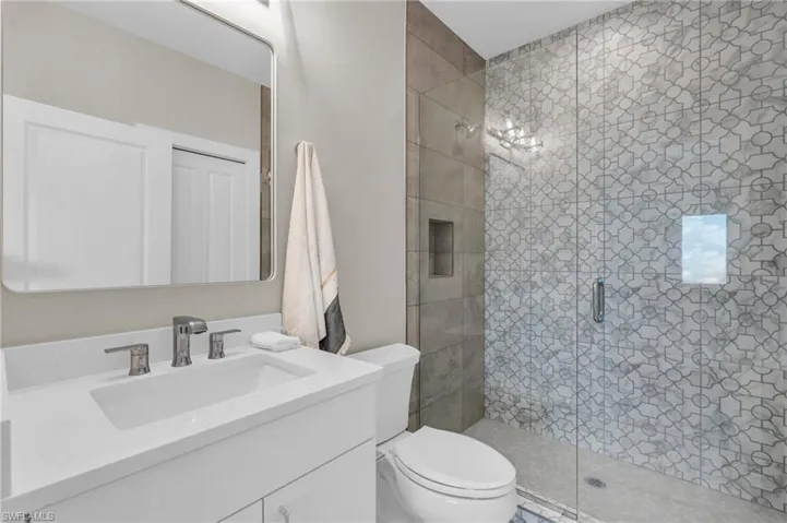 Bathroom featuring toilet, vanity, and walk in shower /  virtually enhanced photo
