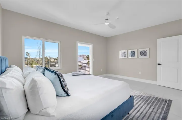 Bedroom with access to outside, ceiling fan, and light tile patterned floors /  virtually enhanced photo