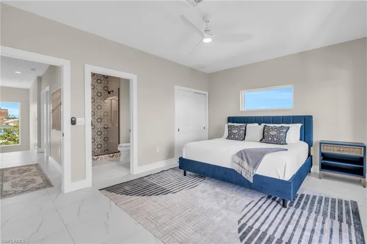 Bedroom featuring a closet, ensuite bath, and ceiling fan /  virtually enhanced photo
