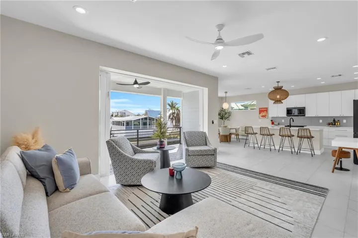 Living room with ceiling fan, light tile patterned floors, and sink /  virtually enhanced photo