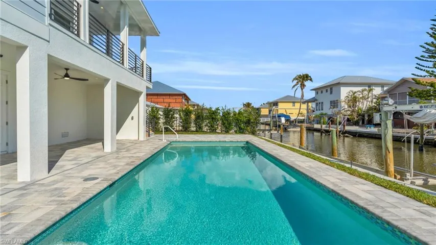 View of swimming pool featuring a patio area, ceiling fan, and a water view VIRTUALLY ENHANCED