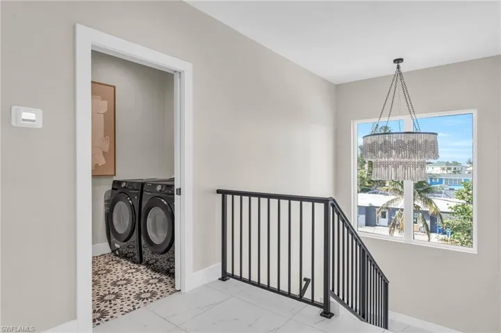 Laundry room with washing machine and clothes dryer, plenty of natural light, and an inviting chandelier