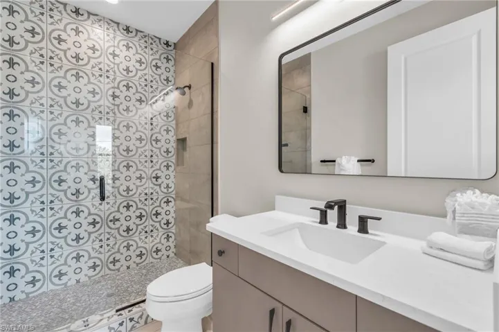 Bathroom with tiled shower, vanity, and toilet /  virtually enhanced photo