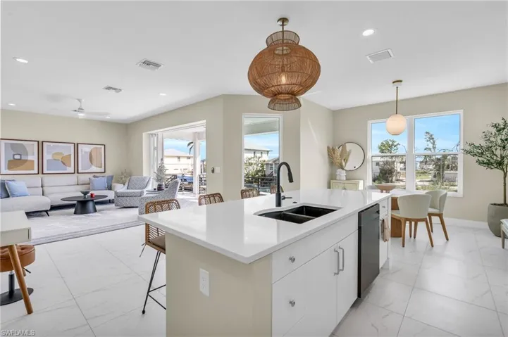 Kitchen featuring ceiling fan, sink, decorative light fixtures, black dishwasher, and white cabinetry /  virtually enhanced photo