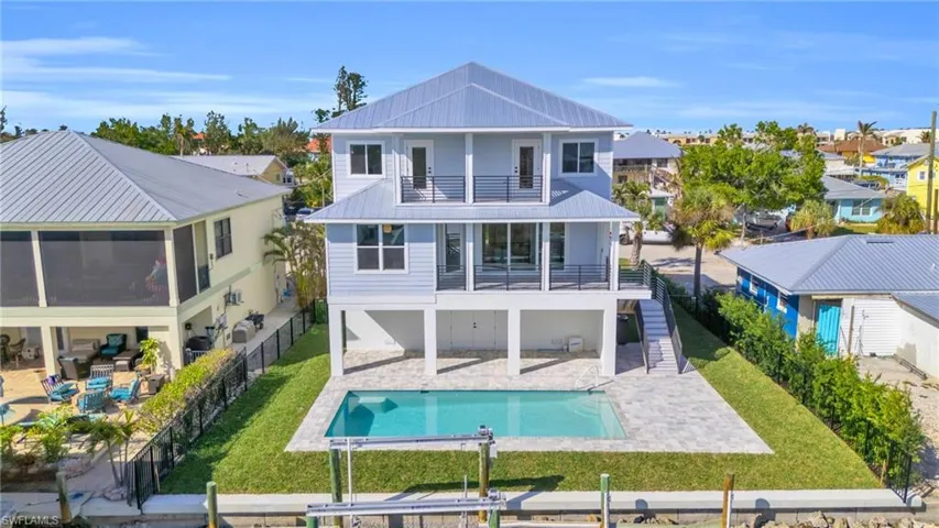 Back of property featuring a fenced in pool, a balcony, a patio, and a lawn VIRTUALLY ENHANCED