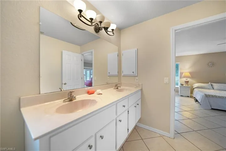 Bathroom featuring tile patterned flooring, a wealth of natural light, a notable chandelier, and vanity
