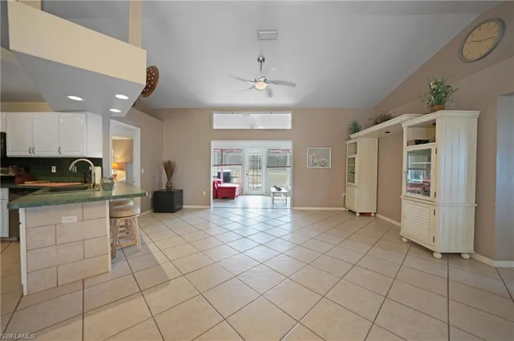 Kitchen featuring kitchen peninsula, sink, white cabinets, a kitchen bar, and decorative backsplash