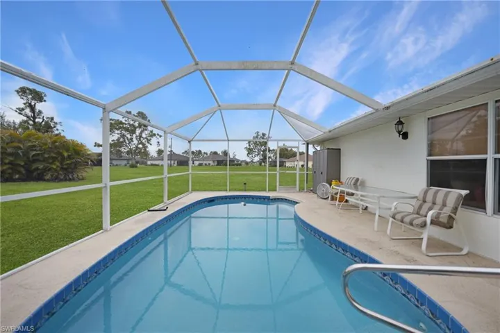 View of swimming pool with screen enclosure, a yard, and a patio