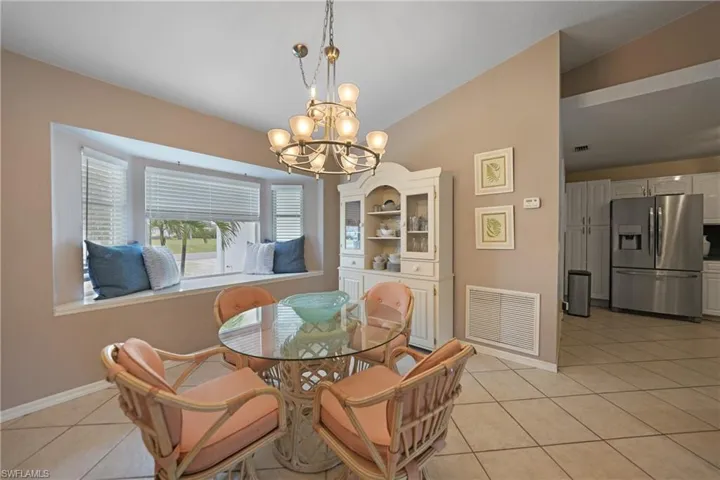 Dining area with lofted ceiling, a notable chandelier, and light tile patterned flooring
