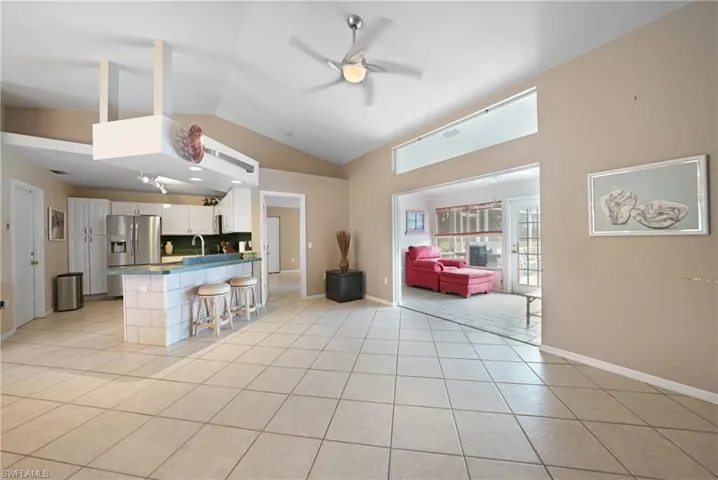 Kitchen with white cabinetry, light tile patterned floors, sink, kitchen peninsula, and a breakfast bar