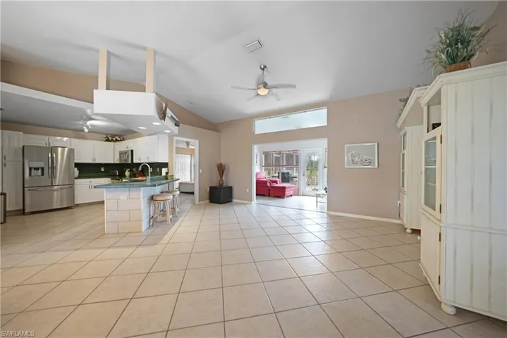 Kitchen featuring backsplash, white cabinetry, stainless steel fridge with ice dispenser, light tile patterned flooring, and a breakfast bar