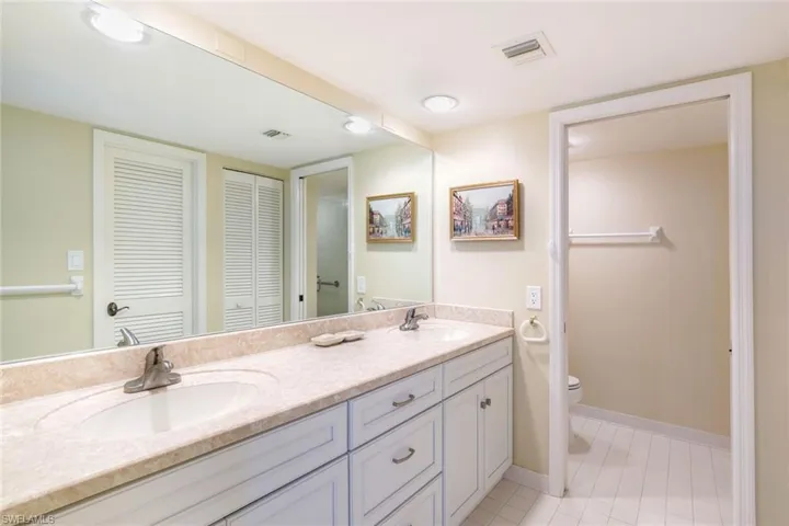 Full bath featuring a closet, double vanity, and light tile patterned floors