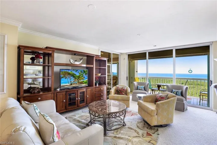 Living area with expansive windows, light carpet, and crown molding