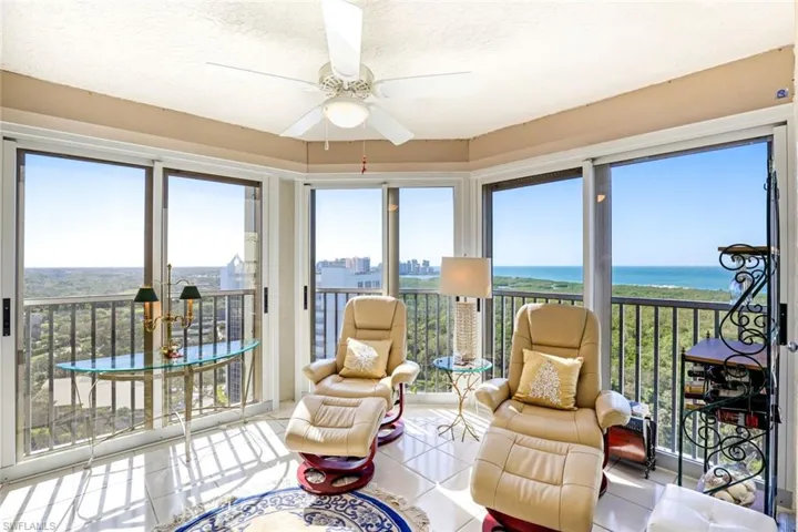 Sunroom with plenty of natural light, tile patterned floors, a city view, a textured ceiling, and a water view