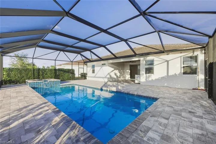 Relaxing pool / spa with a sunroom, a lanai, and a patio area