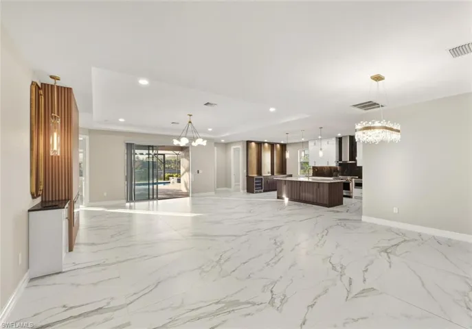 Unfurnished living room featuring a chandelier, a tray ceiling, and wine cooler