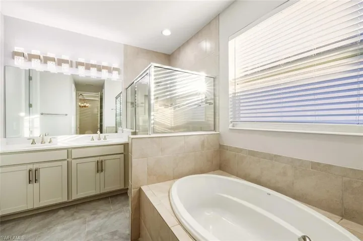 Full bathroom with double vanity, a bath, a shower stall, light tile patterned floors, and recessed lighting