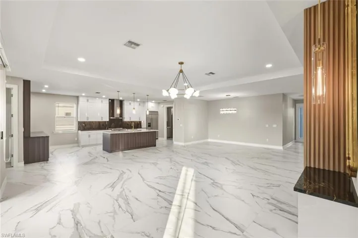 Kitchen with open floor plan, a spacious island, modern cabinets, decorative light fixtures, and a tray ceiling