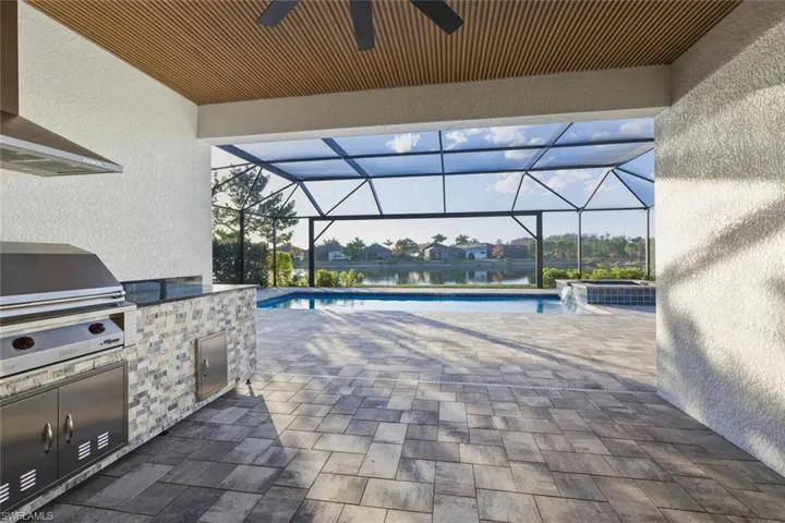View of patio featuring a sunroom, exterior kitchen, a residential view, and glass enclosure