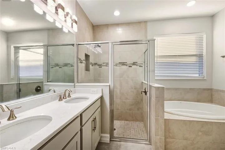 Full bathroom with double vanity, a bath, a stall shower, and recessed lighting