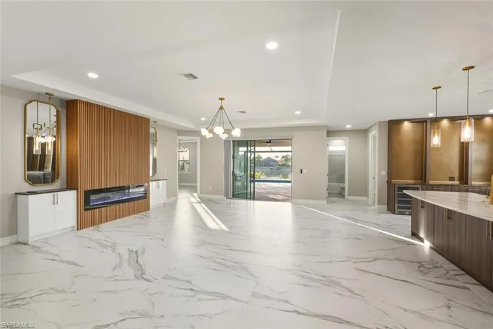 Unfurnished living room with suspended lighting, wine cooler, and light marble finish flooring