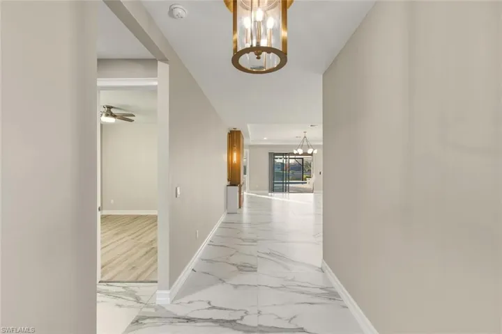 Corridor featuring hanging lights and light marble finish flooring