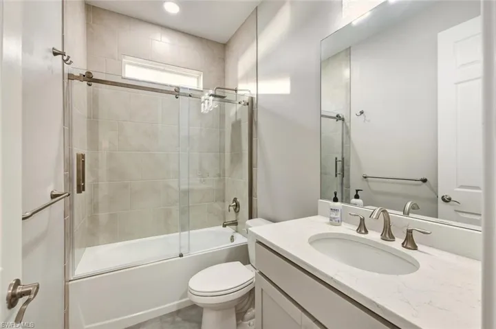 Bathroom with vanity and combined bath / shower with glass door