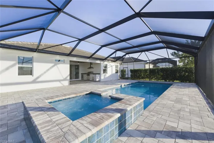 Relaxing pool / spa with a sunroom, a patio area, and glass enclosure