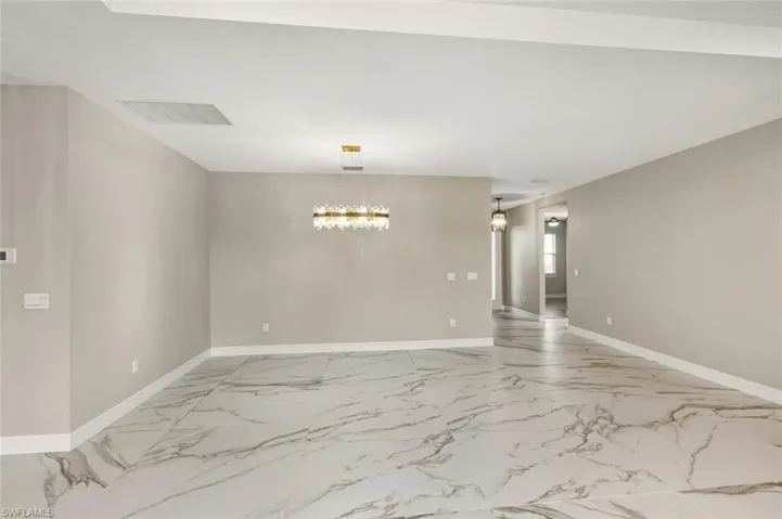 Empty room with light marble finish flooring and suspended lighting