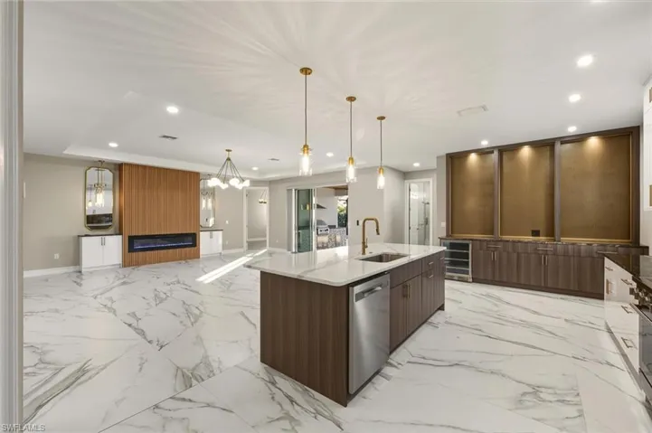 Kitchen featuring dark stone countertops, modern cabinets, open floor plan, a kitchen island with sink, and dual tone cabinetry