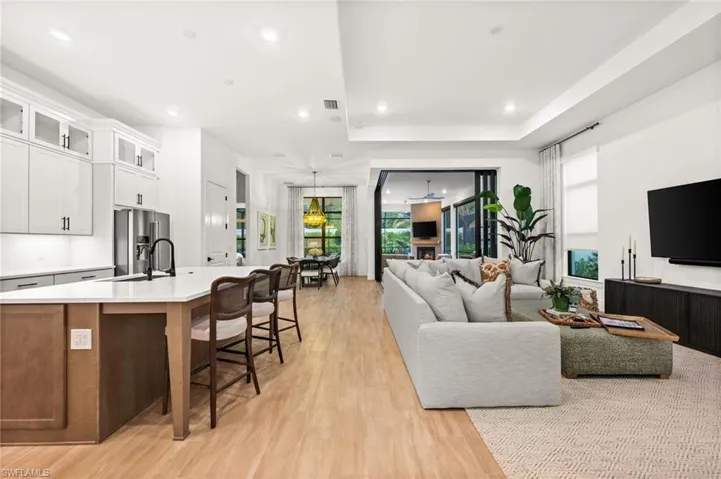 Living area with light wood finished floors, a tray ceiling, recessed lighting, and a chandelier